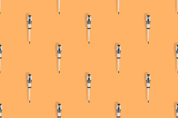 Screwdrivers seamless pattern. Metal screwdrivers with a rubberized handle on an orange background.