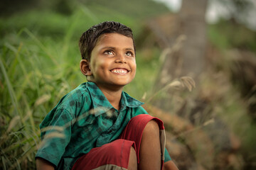 Cute Indian farmer kid portrait on beautiful green farm field, Tamilnadu, India.