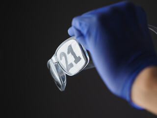 Hand in blue medical gloves holding sunglasses, on lenses are written 2021 year.
