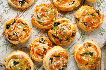 Delicious puff pastry snacks pinwheels with salmon, spinach and mozzarella cheese on a wooden board top view