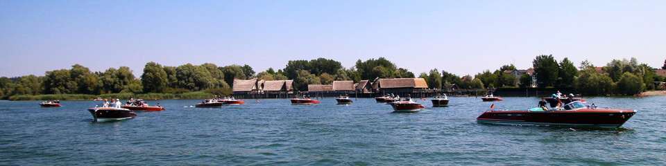 Riva-Boote vor den Pfahlbauten am Bodensee