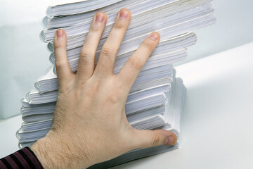 man's hand holds one notebook from a stack of notebooks concept