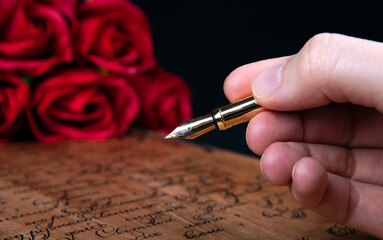 fountain pen in the hand on letter with text and red roses