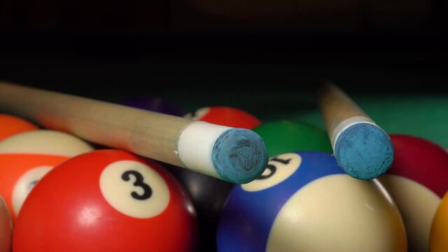 Two cues lie on a triangle with billiard balls on the pool table