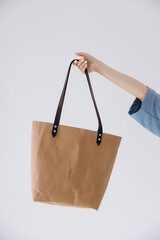 24.06.2020 Vinnitsa, Ukraine: hand of young women with the bag is made of brown paper in hand on a white background
