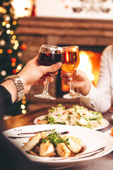 Man and woman drink red and white wine.  Сlose-up of hands with glasses. They celebrate the new year.