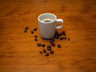 Fresh espresso in white cup with coffee beans around