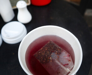 Hot tea cup with fruit tea bag inside on the wooden table