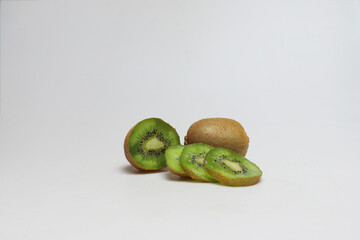 One whole and one half of kiwi fruits with slices next to each other on white background - portrait