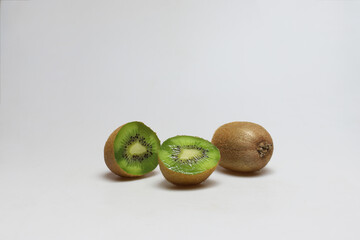 One whole laying and two half of kiwi fruits next to each other  on white background - portrait