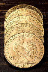 French 20 Francs gold coins (reverse with rooster) on rustic wooden background