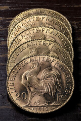 French 20 Francs gold coins (reverse with rooster) on rustic wooden background