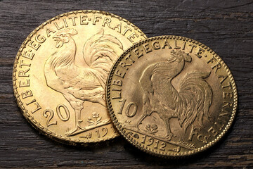 French 10 and 20 Francs gold coins (reverse with rooster) on rustic wooden background