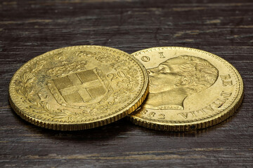 Italian 20 Lira gold coins on rustic wooden background