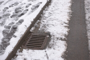 3 - Thawing snow flows into this kerbside drain. Pavement footsteps.