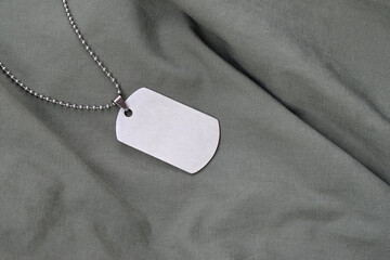 Silvery military beads with dog tag on dark green fatigue uniform