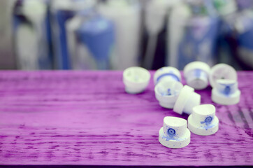 The soiled blue nozzles from the paint sprayer lies on a purple plank on a background of a many...
