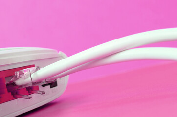 The Internet cable plugs are connected to the Internet router, which lies on a bright pink...