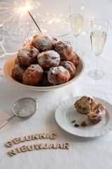 Gelukkig Nieuwjaar (translation: Happy New Year) written with small letters and a bowl of traditional oliebollen (Dutch dough fritters) with sparklers