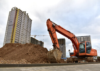 View of a large construction site where earthmoving equipment. Excavator digs the ground to lay...
