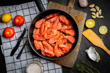 Raw Northern shrimps or prawns with vegetables in a frying pan . Top view