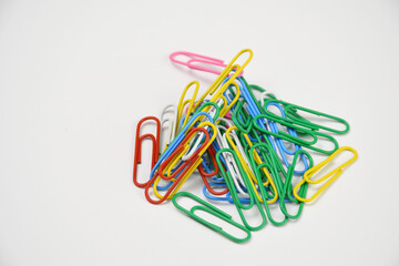 Multicolor plastic paper holders, paperclips on white background.