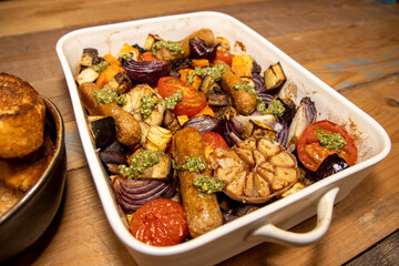 A baking trey of sausages and vegetables with tarragon relish