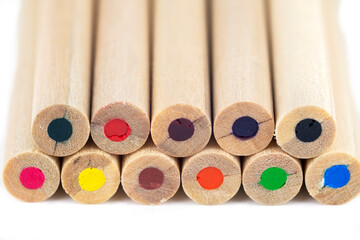 light wooden colored pencils close up on white blurred background