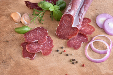 Slices of delicious spanish sausage fuet on the wooden natural kitchen board closeup. Love food concept. Traditional Spanish sausage. Variety of dry cured chorizo. Heart shaped sausage.