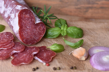 Slices of delicious spanish sausage fuet on the wooden natural kitchen board closeup. Love food concept. Traditional Spanish sausage. Variety of dry cured chorizo. Heart shaped sausage.