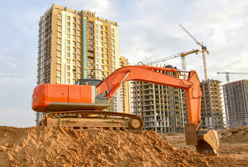 Excavator during excavation aond road construction works at construction site on sunset background....