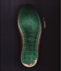 Ein gebrauchter grüner Turnschuh, Blick auf die schäbige Schuhsohle