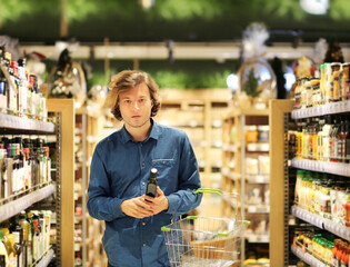 Teenager shopping in supermarket, reading product information.