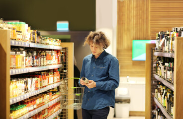 Teenager shopping in supermarket, reading product information.