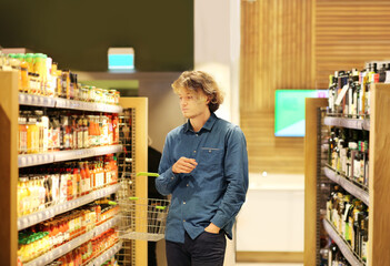 Teenager shopping in supermarket, reading product information.