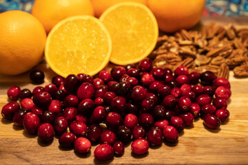 Deconstructed cranberry sauce on a wooden board, with pecans and sliced oranges