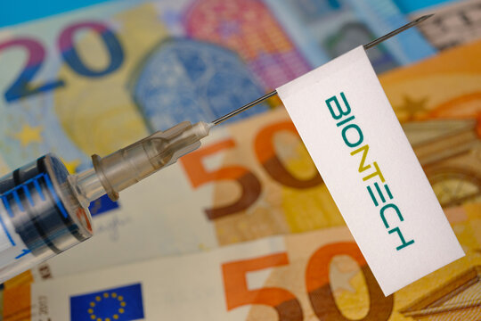 Stafford / United Kingdom - November 22 2020: BionTech vaccine Covid-19 concept. Syringe needle and sticker on it, blurred euros on the background. Real photo, not a montage.