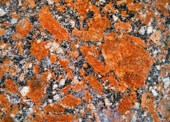 Grunge background from red granite natural stone texture. Polished surface, copy space.