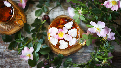 Selective focus. Rosehip tea. Pink flowers and leaves of rose hips.