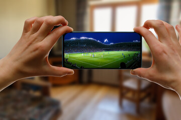 Watching football game at home via smartphone. Broadcasting soccer from the stadium.