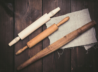 wooden rolling pins for rolling dough on a black background, new and very old utensils