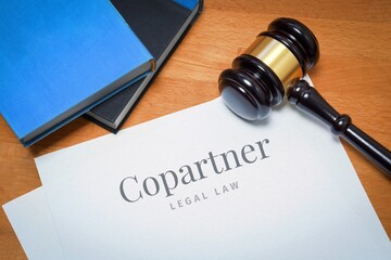 Copartner. Document with label. Desk with books and judges gavel in a lawyer's office.