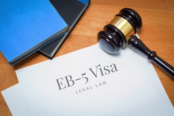 EB-5 Visa. Document with label. Desk with books and judges gavel in a lawyer's office.