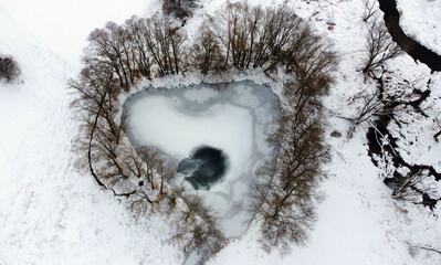 Luftaufnahme von einer Drohne von einem zugefrorenen See in Herzform oder Dreiecksform im Winter