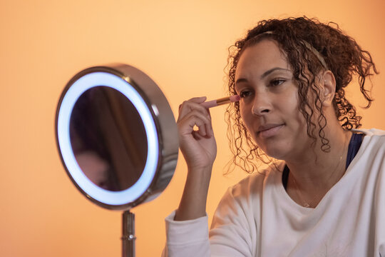 ethnic woman using beauty and make up products in front the mirror,