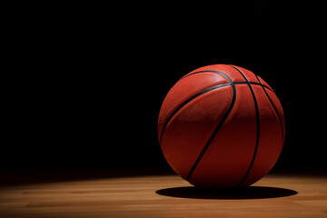 BASKETBALL BALL ON WOODEN COURT ON DARK BACKGROUND. BETS IN SPORTS. COPY SPACE.