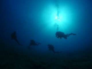 Fototapeta na wymiar silhouette scuba divers sun beam shine rays underwater lady woman diver relaxing blue ocean scenery of person