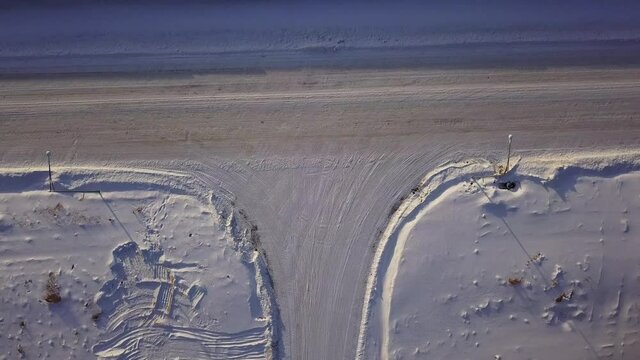 T-shaped crossroad on a winter sunny day. Action. Aerial top view of a countryside road segment covered by snow.