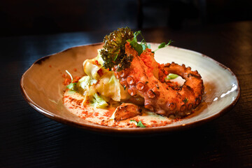 Grilled octopus with sauce. Vegetable garnish with bacon crumbs.