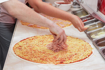 The process of making pizza. Hands of chef baker making pizza at cafe kitchen